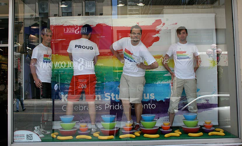 store front window with 4 guys wearing rainbow t-shirts, rainbow poster, and rainbow coloured products