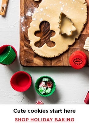 overhead view of cutting board with cookie dough, red & green silicone cpcake holders, cookie ctters and cookie stamps