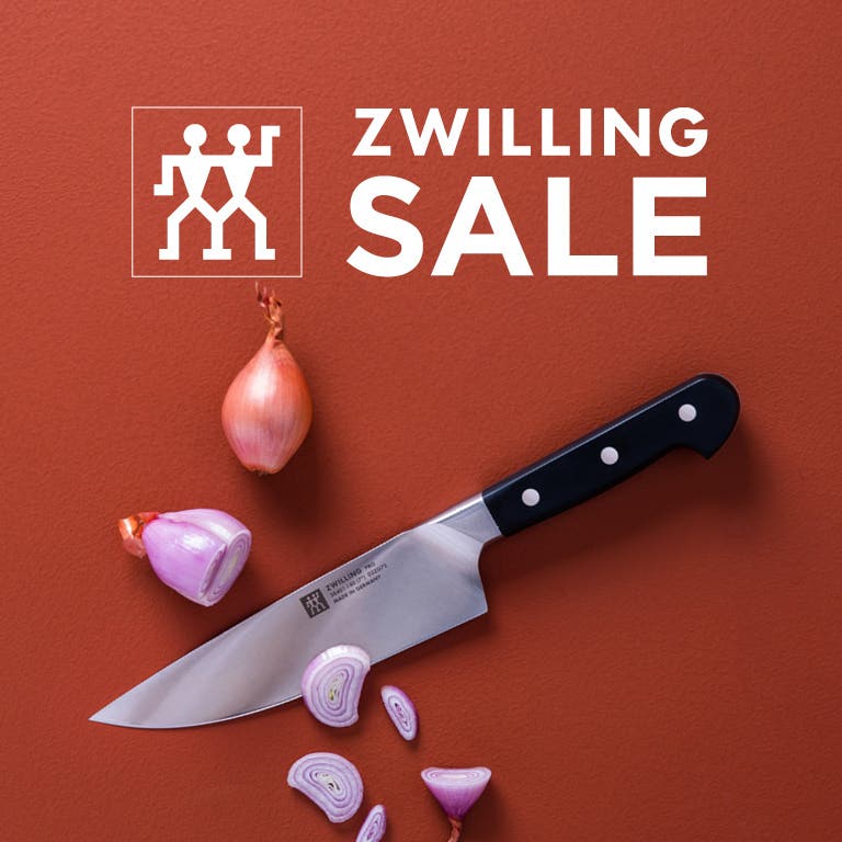 ZWILLING SALE logo, Chef Knife with sliced garlic on a medium brown background