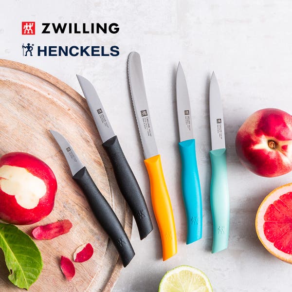 5 different colour Twin Grip II knives on a cutting board with cut fruit and vegetables