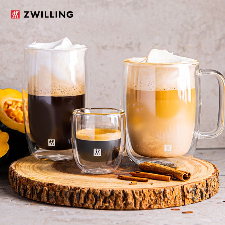 3 different size double wall glasses with different coffee drinks on a wood tray