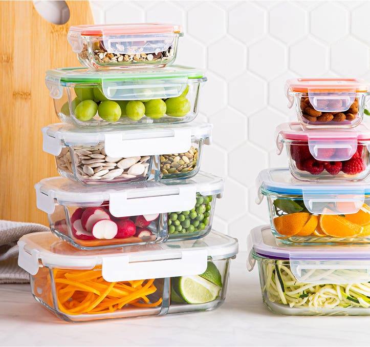 2 stacks of glass food storage containers filled with different food, on a kitchen countertop